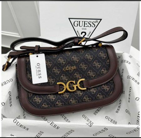 حقيبة نسائية أنيقة بتصميم فاخر ونقشة مميزة من GUESS، مع تفاصيل جلدية وإغلاق ذهبي أنيق يبرز فخامتها. عملية وعصرية، مثالية للاستخدام اليومي والمناسبات لإطلالة راقية وجذابة.