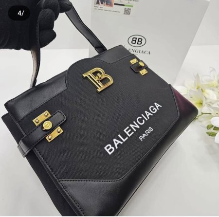 حقيبة فاخرة من Balenciaga بتصميم أسود عصري وشعار Paris الأيقوني مع تفاصيل ذهبية جريئة. مزيج مثالي بين الفخامة والستايل العصري، لإطلالة قوية تعكس ذوقًا راقيًا وحضورًا لافتًا في كل مناسبة.