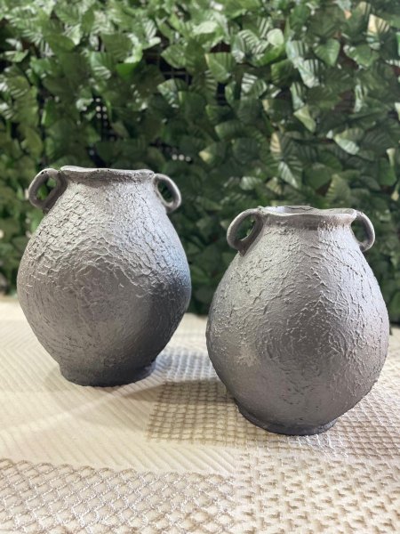 فازتان ديكور بتصميم مستوحى من الطراز التراثي وملمس حجري مميز، بلون رمادي مطفي أنيق. تضيفان طابعاً دافئاً وطبيعياً لأي مساحة، مثاليتان للديكور العصري أو الريفي، وتبدوان جميلتين مع الورد الجاف أو كقطعة ديكور مستقلة.