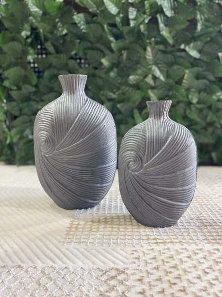 فازتان ديكور بتصميم حلزوني أنيق ولمسة فنية مميزة، بلون رمادي مطفي هادئ. تضيفان طابعاً عصرياً راقياً لأي مساحة، مثاليتان للطاولات والرفوف وزوايا الصالون، وتبدوان رائعتين مع الورد الجاف أو كقطعة ديكور مستقلة.